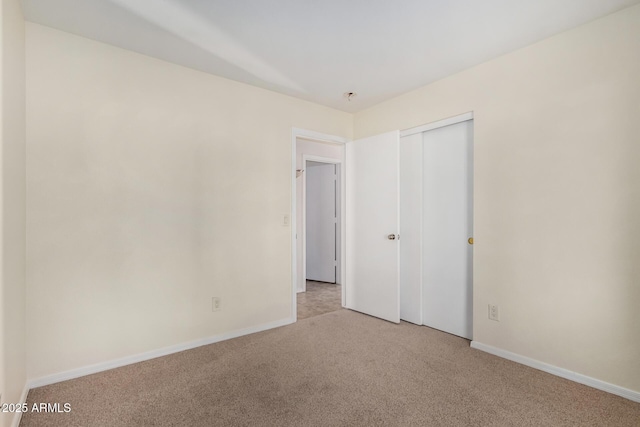 unfurnished bedroom with light colored carpet and a closet