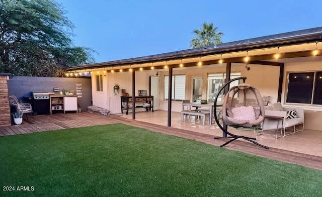 back house at dusk with a lawn and a patio area