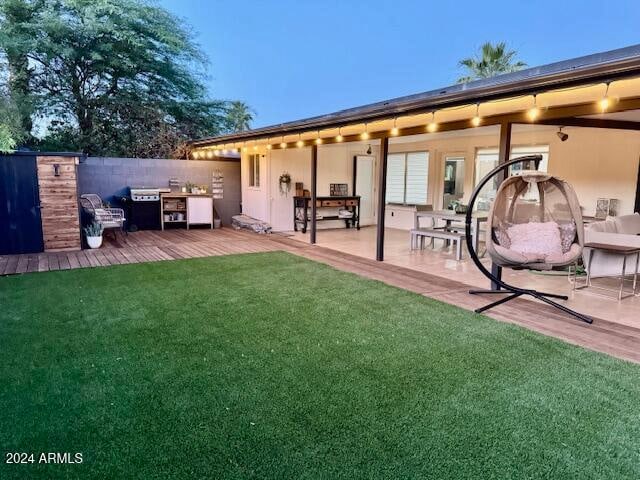 back house at dusk featuring a lawn and a patio area