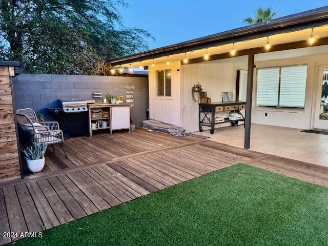 wooden deck featuring a lawn and a patio