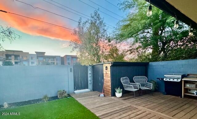 deck at dusk featuring a grill