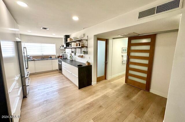 kitchen featuring white cabinets, light wood-type flooring, and sink