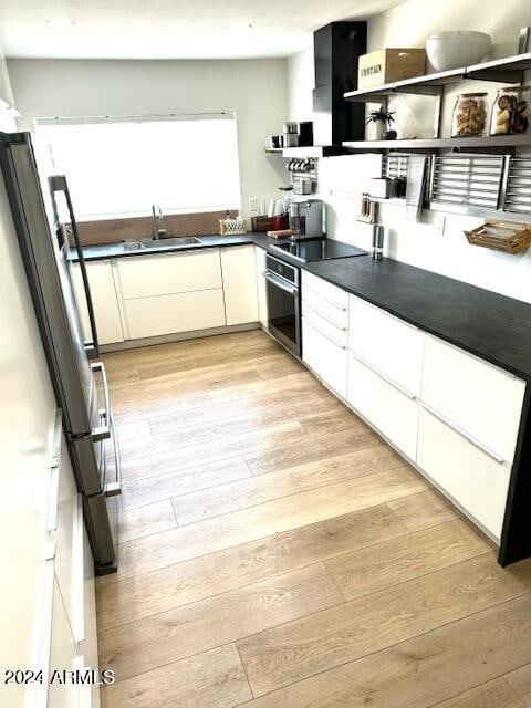 kitchen with light hardwood / wood-style flooring, white cabinetry, appliances with stainless steel finishes, and sink