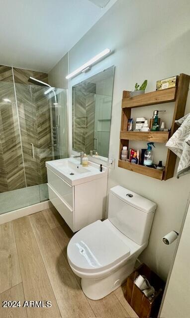 bathroom with hardwood / wood-style floors, vanity, a shower with shower door, and toilet