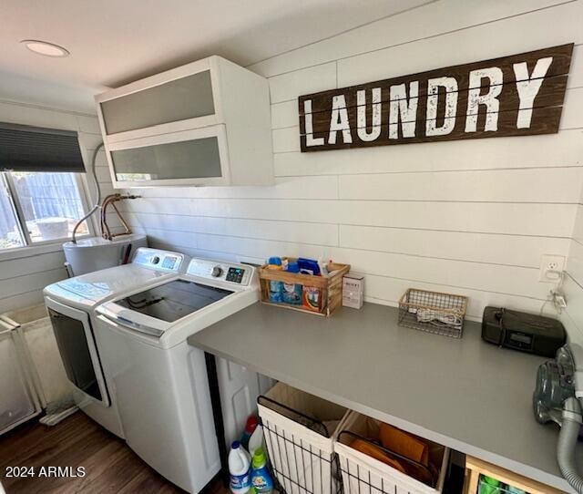 clothes washing area with separate washer and dryer, wooden walls, and dark hardwood / wood-style flooring