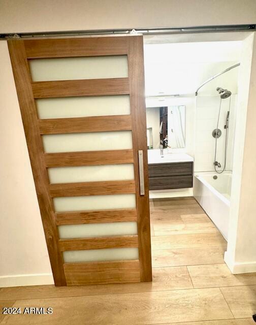 bathroom with wood-type flooring, vanity, and  shower combination