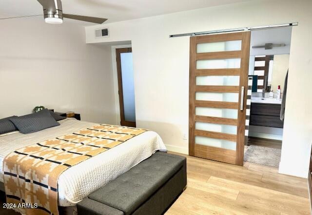 bedroom with ceiling fan, light wood-type flooring, and ensuite bath