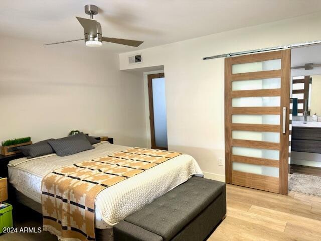 bedroom with light wood-type flooring, ensuite bath, and ceiling fan