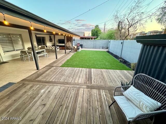 deck at dusk with a yard and a patio area