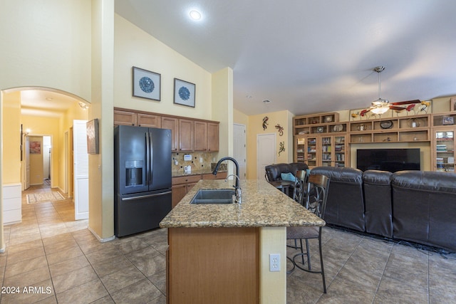 kitchen featuring a breakfast bar, black refrigerator with ice dispenser, ceiling fan, sink, and tile patterned floors