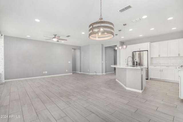 kitchen featuring light wood-type flooring, ceiling fan with notable chandelier, and decorative light fixtures