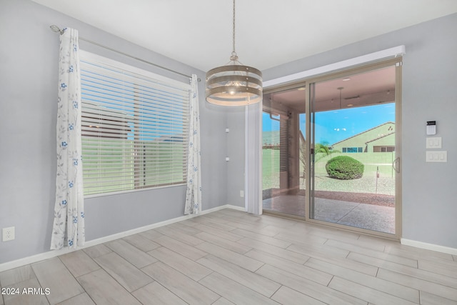 spare room with a notable chandelier and light hardwood / wood-style flooring