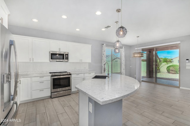 kitchen featuring stainless steel appliances, hanging light fixtures, sink, and white cabinetry