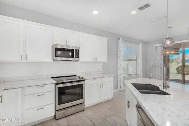 kitchen featuring white cabinetry, appliances with stainless steel finishes, hanging light fixtures, and sink