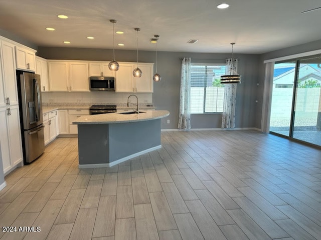 kitchen featuring decorative light fixtures, sink, stainless steel appliances, and white cabinets