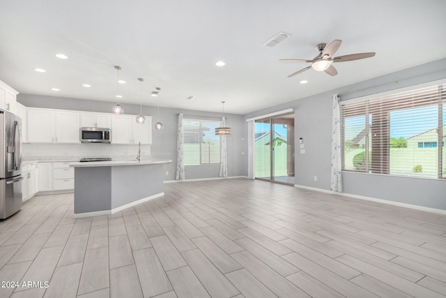 kitchen with light hardwood / wood-style floors, white cabinets, stainless steel appliances, decorative light fixtures, and ceiling fan