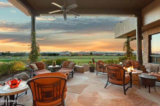 patio terrace at dusk with a fire pit and ceiling fan