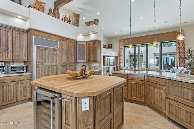 kitchen featuring hanging light fixtures, a kitchen island, beverage cooler, and decorative backsplash