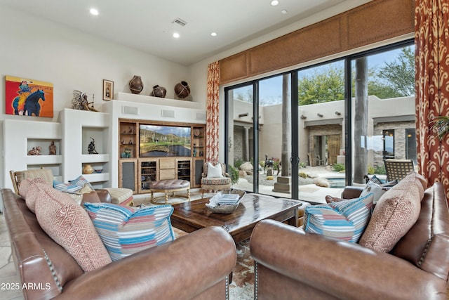 living room featuring a towering ceiling, built in features, and a fireplace