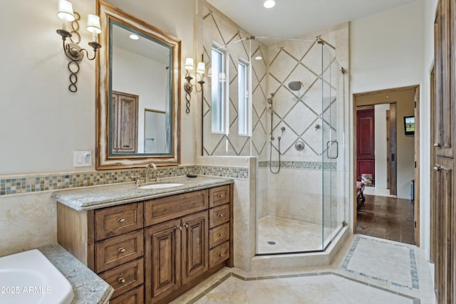 bathroom with a shower with door, vanity, and tile walls