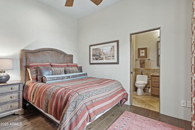 bedroom with tile walls, connected bathroom, dark wood-type flooring, and ceiling fan