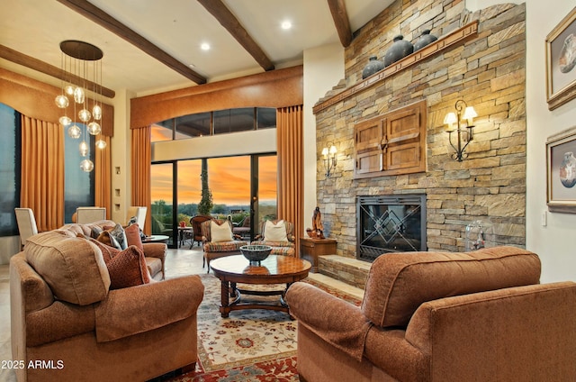 living room featuring beamed ceiling, a stone fireplace, and an inviting chandelier