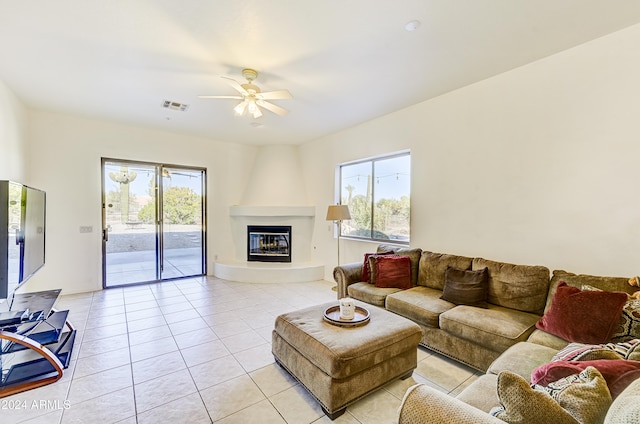 tiled living room featuring ceiling fan and a fireplace