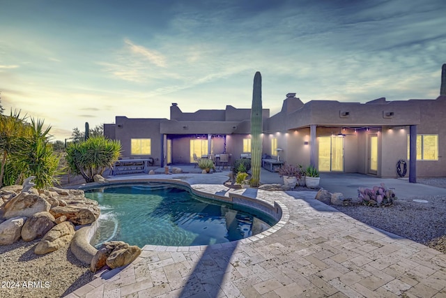 pool at dusk featuring a patio area