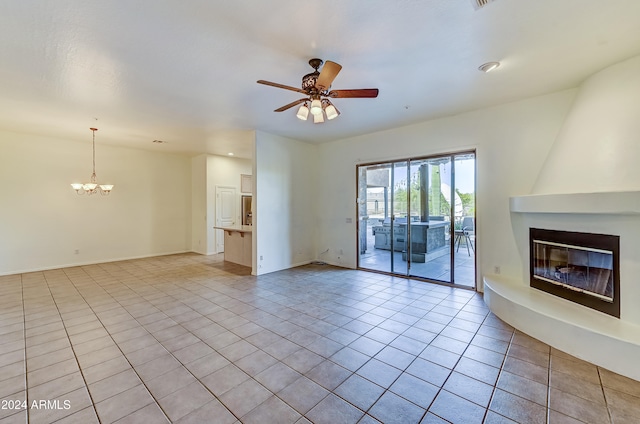 unfurnished living room with a large fireplace, light tile patterned flooring, and ceiling fan with notable chandelier