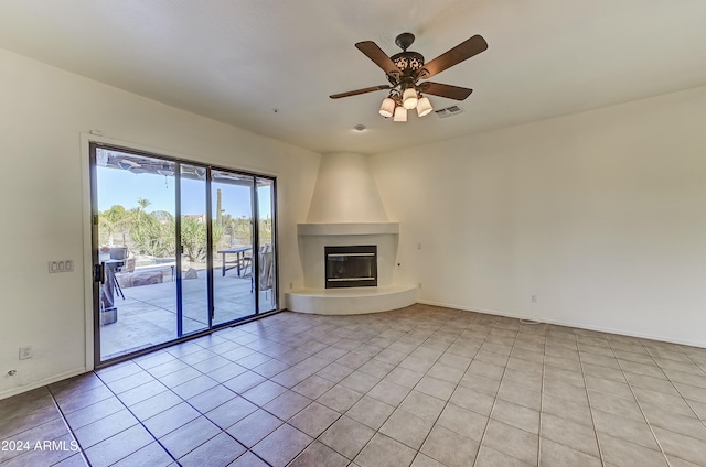 unfurnished living room featuring light tile patterned floors, ceiling fan, and a large fireplace