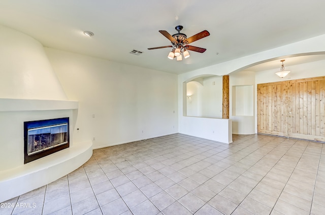 unfurnished living room featuring ceiling fan, light tile patterned flooring, and a fireplace