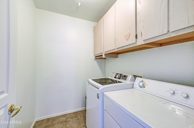 clothes washing area with cabinets, light tile patterned floors, and washer and clothes dryer