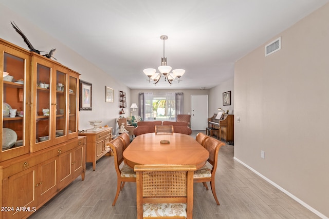 dining room featuring a chandelier, baseboards, visible vents, and light wood-style floors