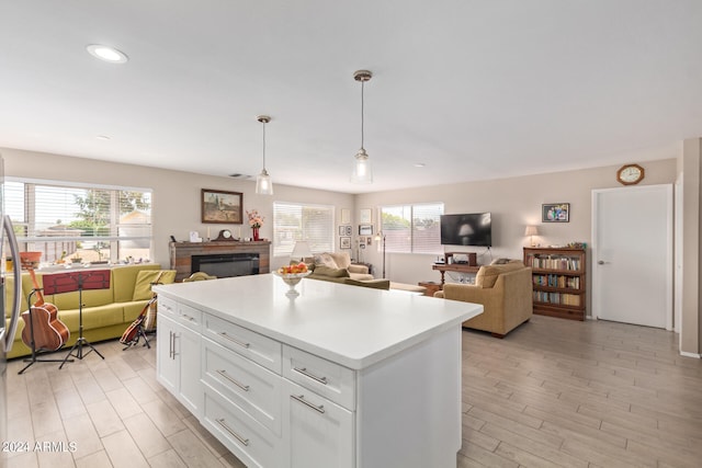 kitchen featuring white cabinets, open floor plan, light countertops, hanging light fixtures, and a center island