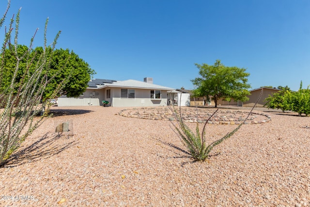 rear view of property with fence and roof mounted solar panels