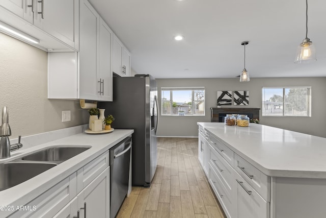 kitchen featuring dishwasher, light countertops, a sink, and white cabinets