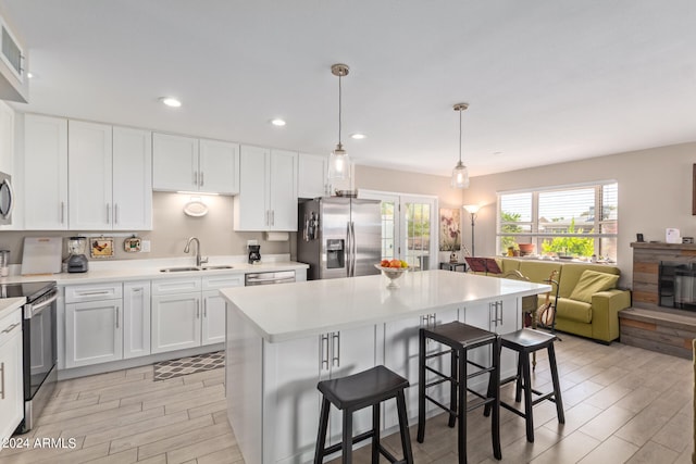 kitchen featuring hanging light fixtures, white cabinets, appliances with stainless steel finishes, and sink