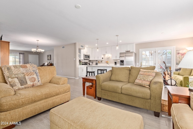 living room with light wood-type flooring, recessed lighting, a healthy amount of sunlight, and a notable chandelier