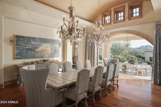 dining space with hardwood / wood-style floors, high vaulted ceiling, and a chandelier