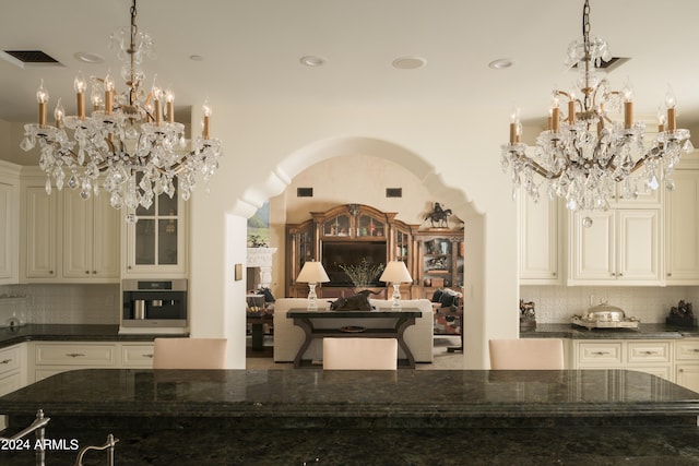 kitchen with pendant lighting, dark stone countertops, oven, and tasteful backsplash