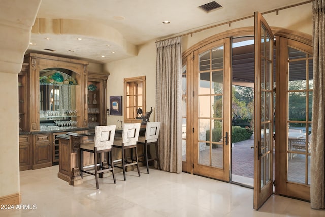 bar featuring light tile patterned flooring, a wealth of natural light, dark stone counters, and french doors