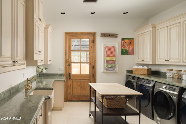 clothes washing area with light tile patterned floors, cabinets, and washer and clothes dryer