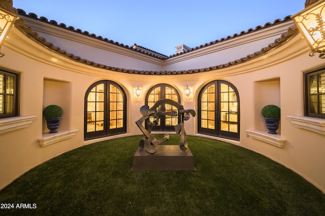 back house at dusk featuring a yard and french doors