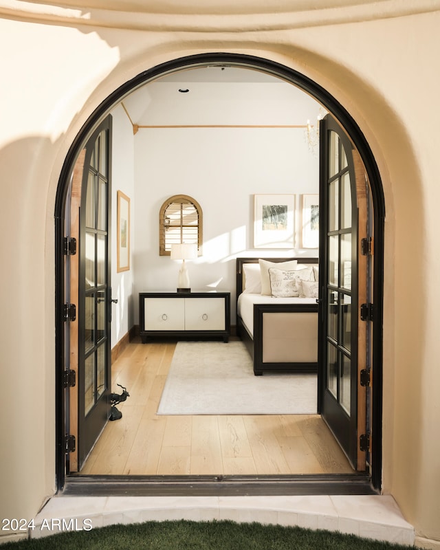 bedroom with light hardwood / wood-style flooring, multiple windows, and french doors