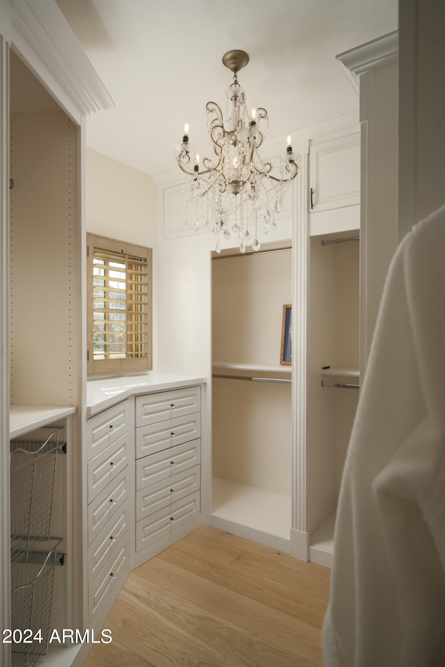 spacious closet with an inviting chandelier and light wood-type flooring