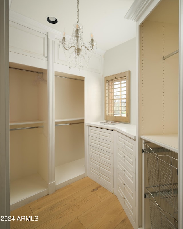 walk in closet with an inviting chandelier and light hardwood / wood-style flooring