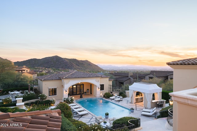 pool at dusk with a patio and a mountain view