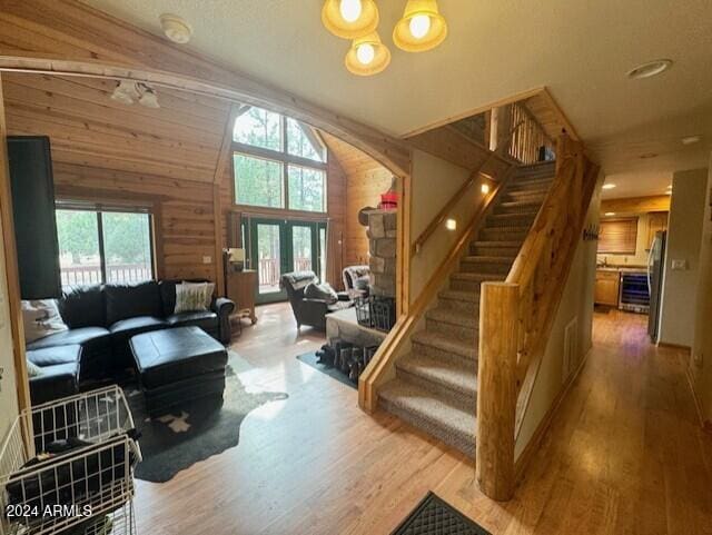 living room with wood walls, lofted ceiling, a chandelier, and hardwood / wood-style flooring