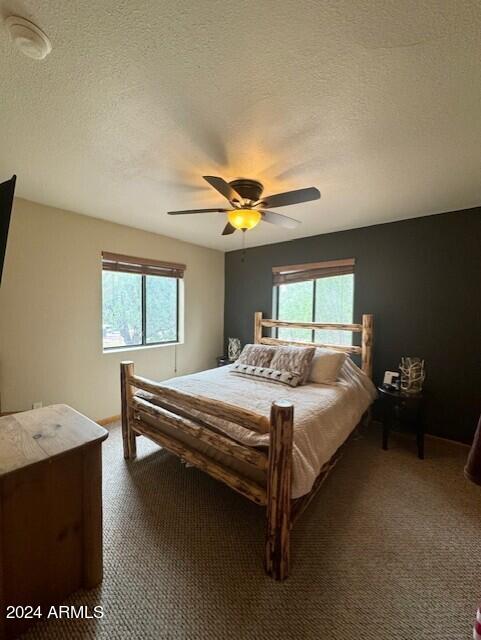 carpeted bedroom with ceiling fan and a textured ceiling