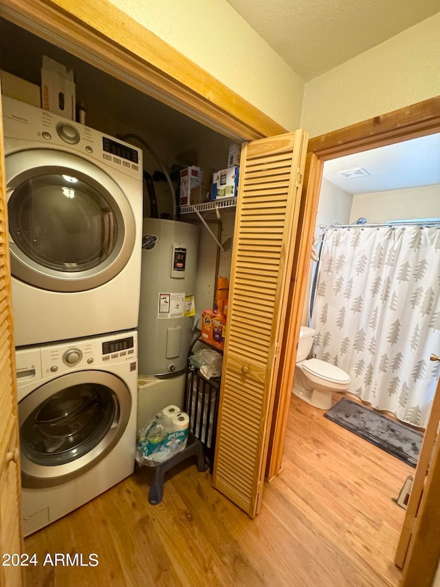 laundry area with stacked washer and dryer, hardwood / wood-style floors, and electric water heater